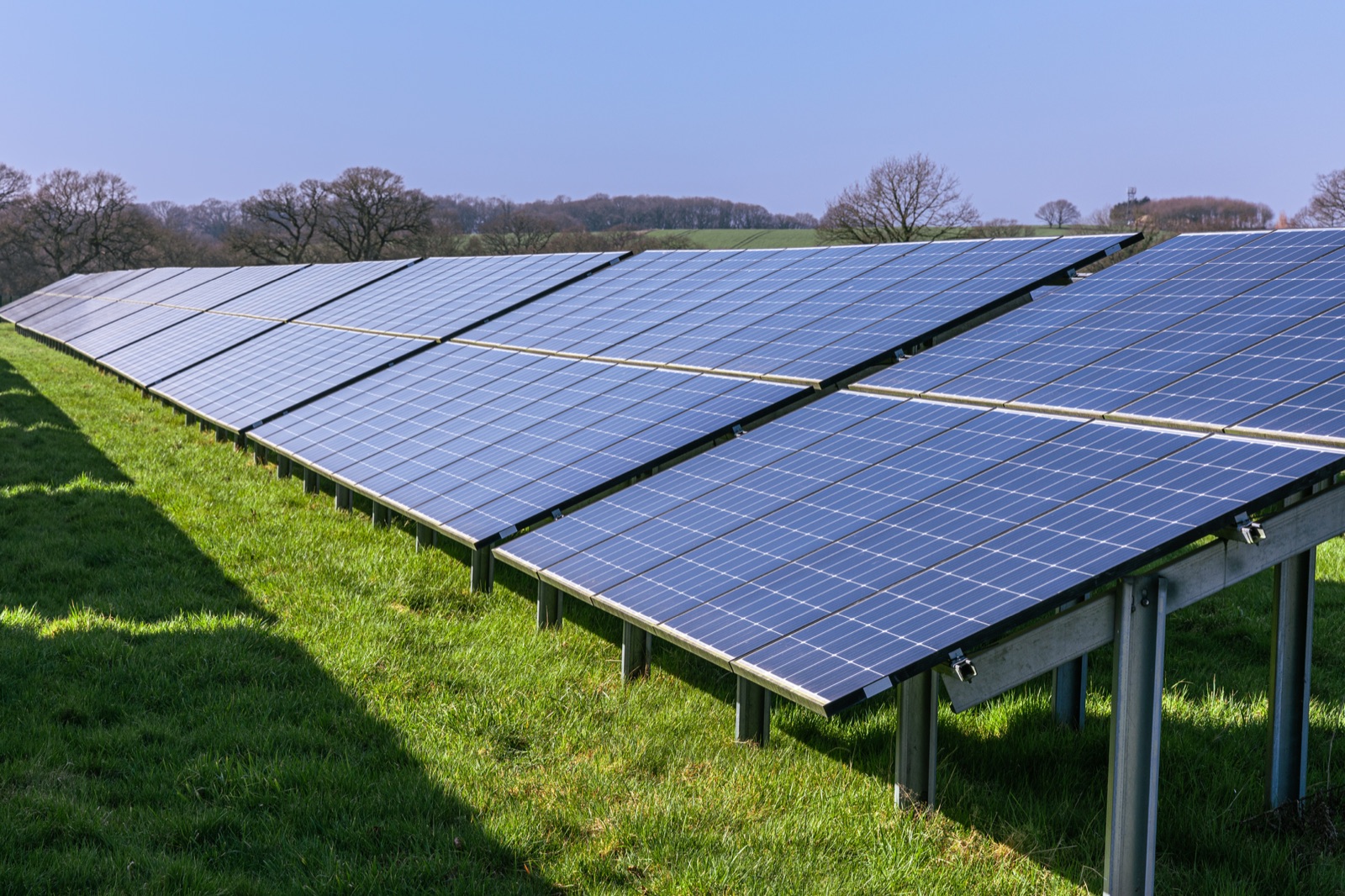 Fixed-tilt ground-mount solar array rows on grass